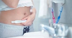 Image of a woman holding an at home pregnancy test 