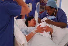 Image of nurses and new mom holding a baby 