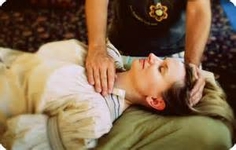 Image of practitioner performing Reiki on a woman with hands positioned over the throat and top of the head 