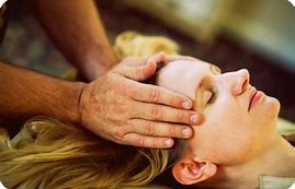Image of patient receiving reiki energy healing, with hand placement on both temples 